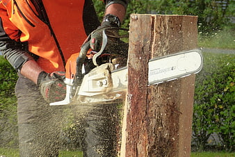 Worker Cutting Wood with Chainsaw Outdoors