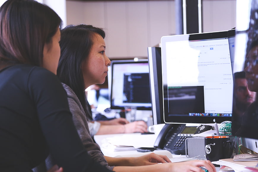 Two women working at computers in a modern office