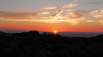 Vibrant sunset over rocky mountain landscape with orange sky
