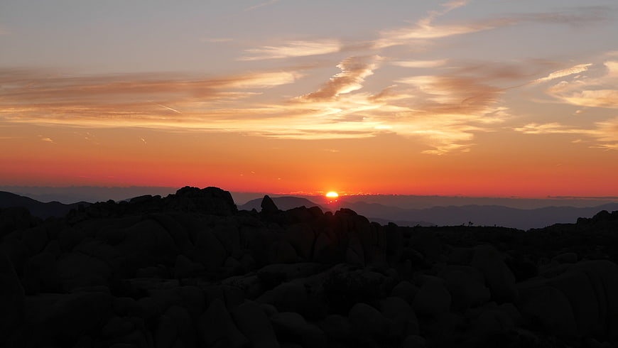 Vibrant sunset over rocky mountain landscape with orange sky