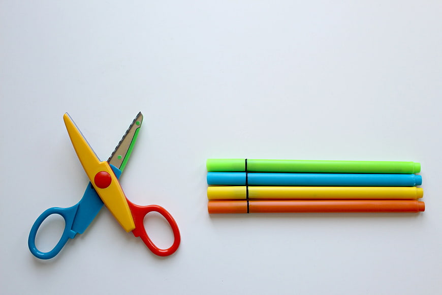 Colorful safety scissors and markers on white background