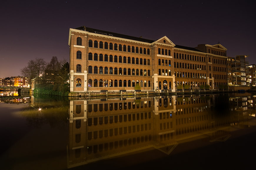 Night view of historic brick building reflected in canal water