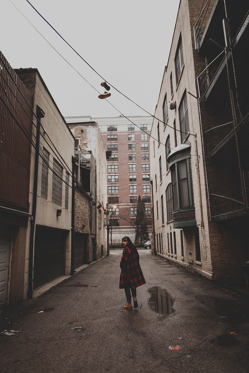 Woman in Red Plaid Coat Walking in Urban Alley