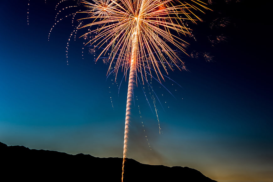 Golden Fireworks Exploding Over Silhouette Mountain Sky