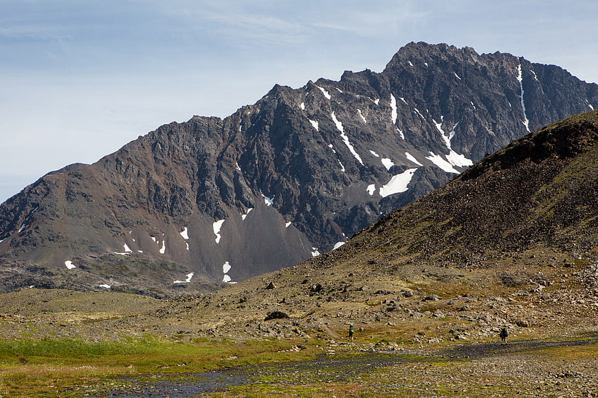 Hikers in Rocky Mountain Landscape with Snow Patches