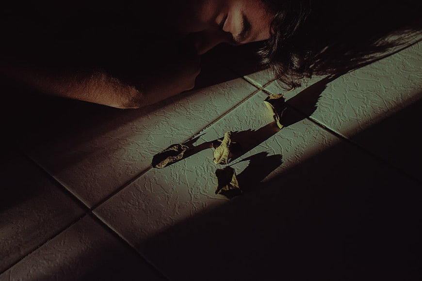 Man Sleeping on Floor with Dried Leaves in Shadows
