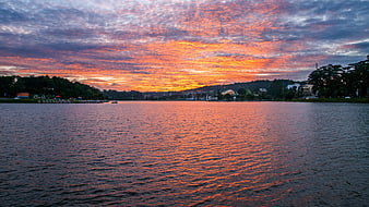 Vibrant Orange Sunset Sky Over Calm Lake Water