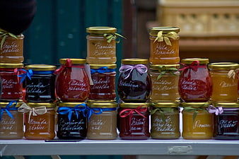 Assorted homemade fruit jams in glass jars with gold lids and ribbons