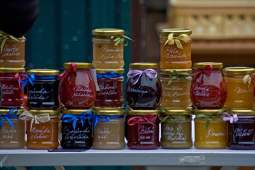 Assorted homemade fruit jams in glass jars with gold lids and ribbons