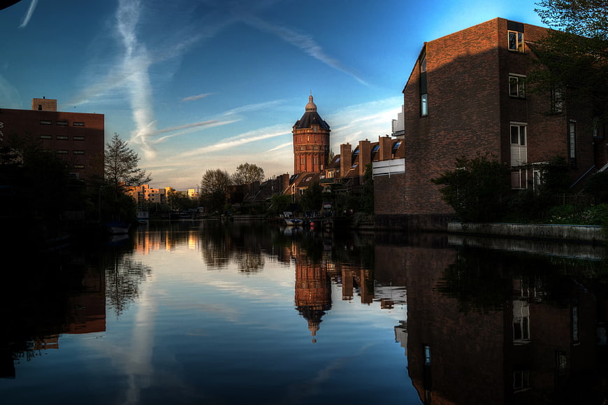 Water tower reflection in canal at sunset