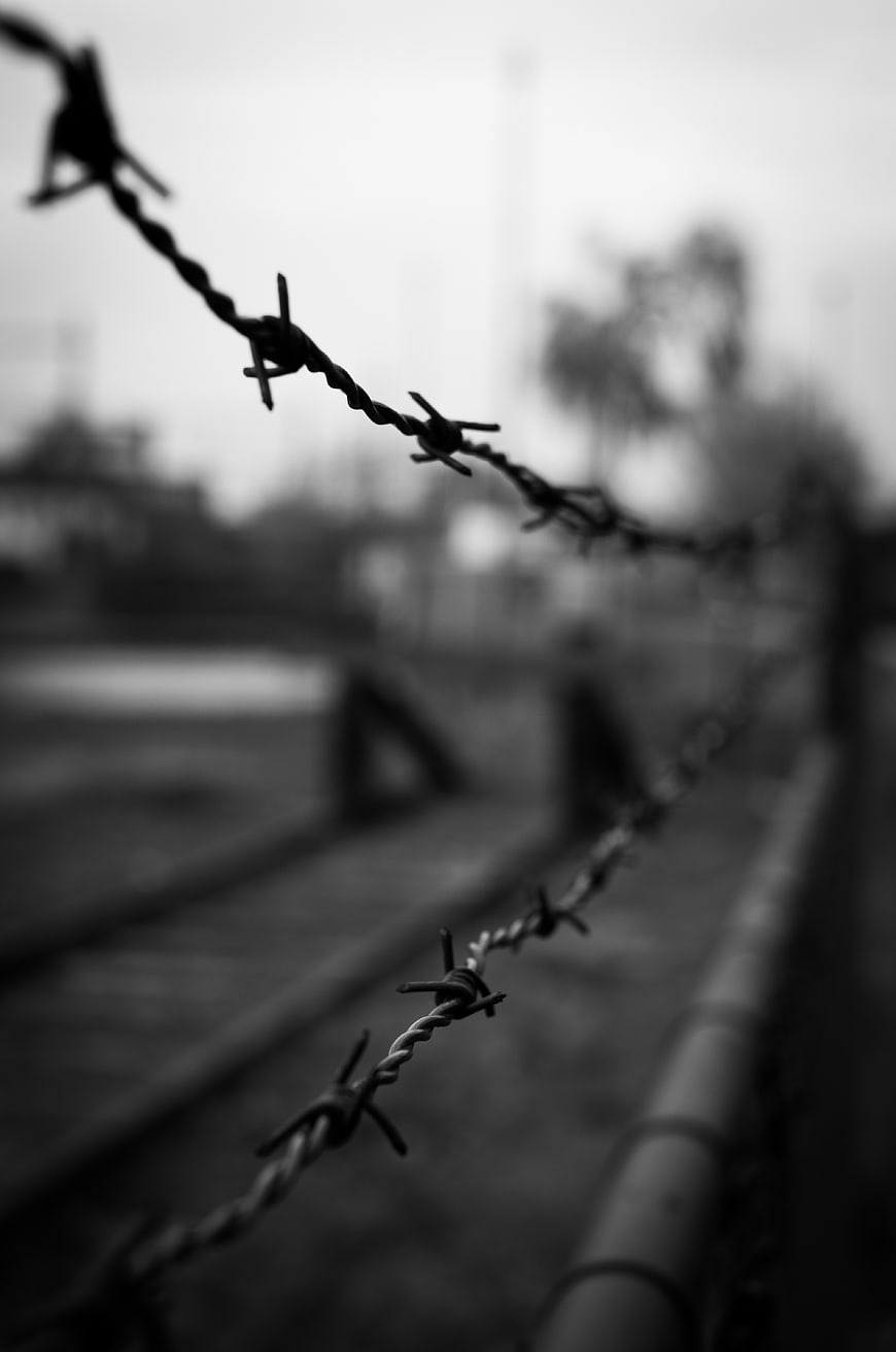 Black and white barbed wire fence along railroad tracks