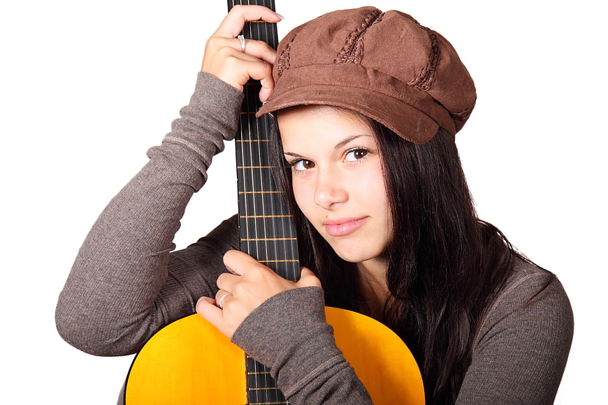Young woman with acoustic guitar and brown cap