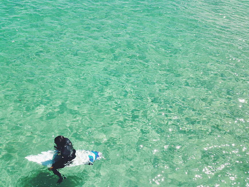 Aerial view of surfer in turquoise ocean water