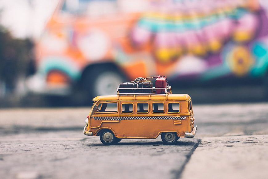 Vintage yellow toy bus with luggage on roof rack