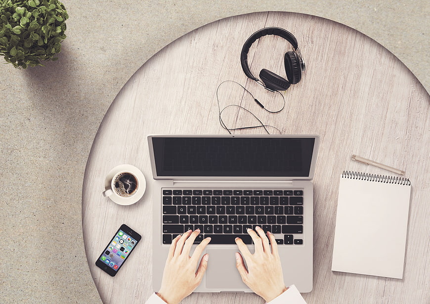 Top view of workspace with laptop, coffee, and headphones