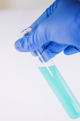 Gloved Hand Holding Test Tube with Blue Liquid