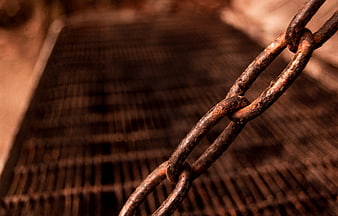 Close-up of rusty metal chain on industrial grate background
