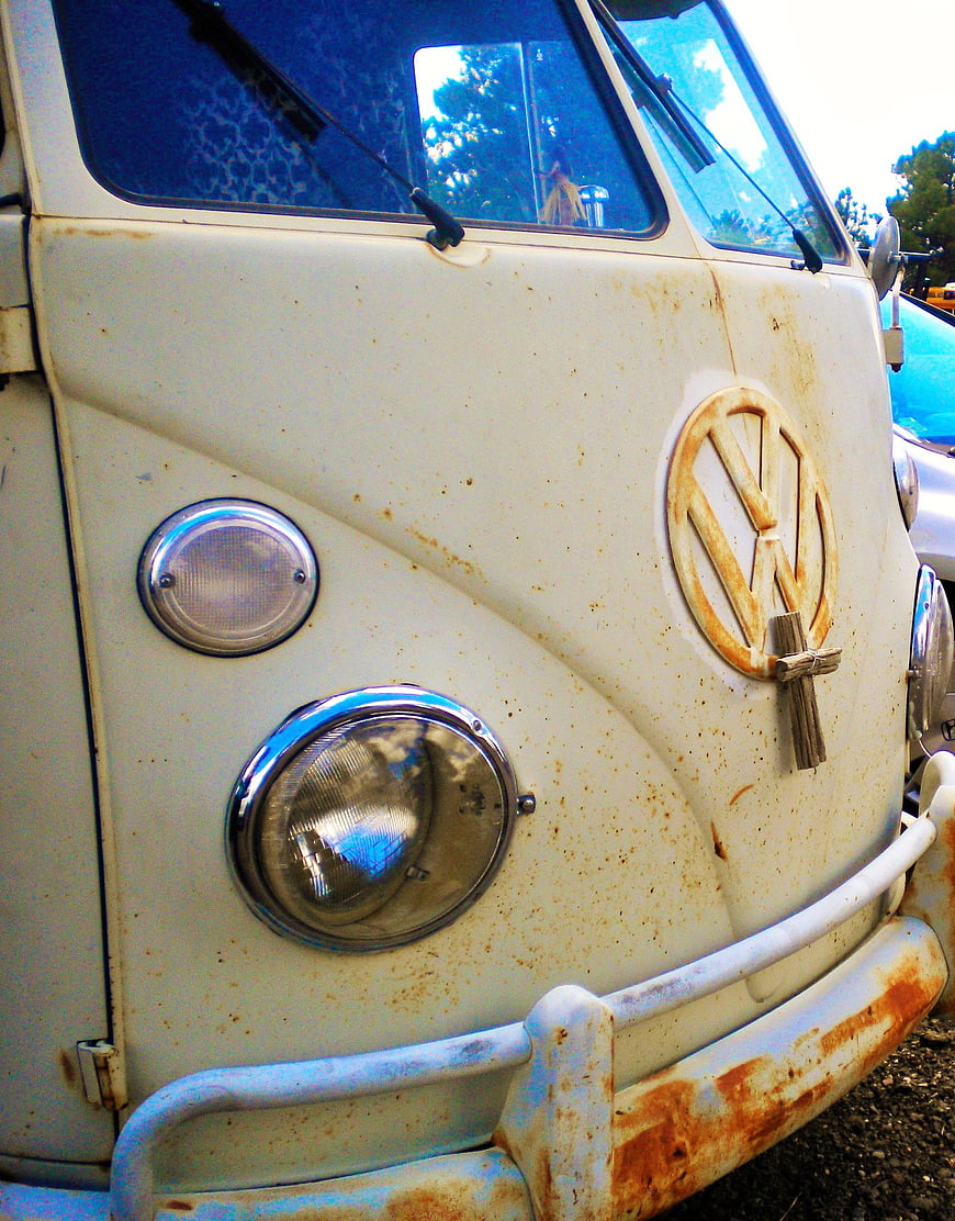 Close-up of vintage white VW van with rust and wooden cross