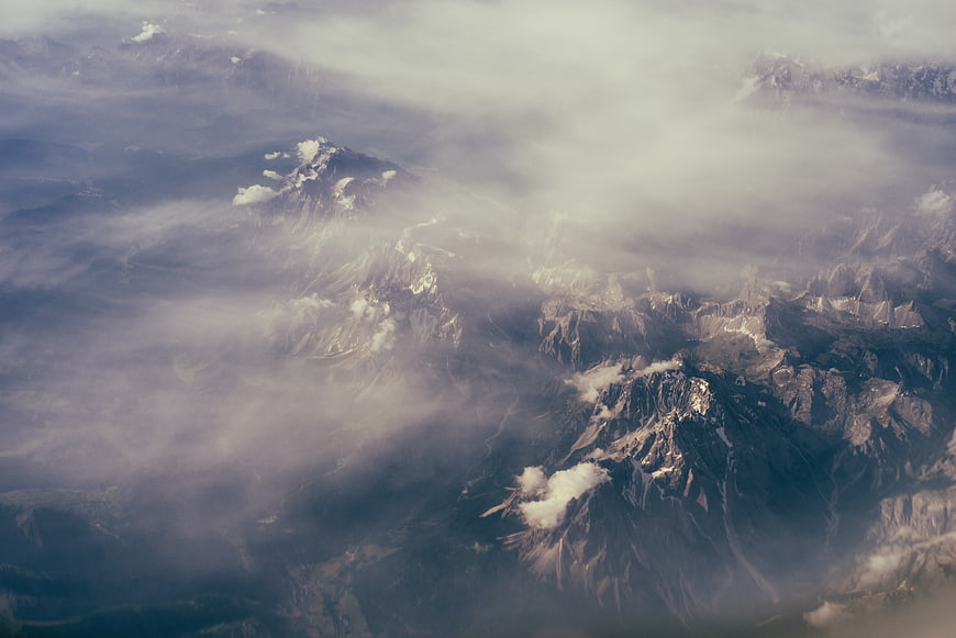 Aerial view of misty mountain peaks through clouds