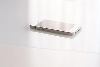 White smartphone on white surface with reflection