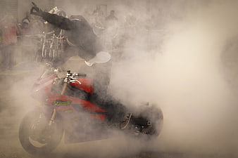 Motorcyclist performing a burnout stunt with heavy smoke