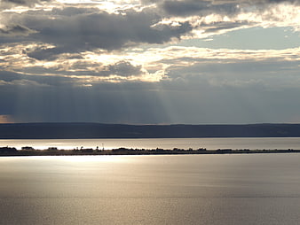 Dramatic Sun Rays Over Calm Lake and Distant Hills