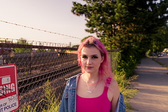 Young Woman with Pink Hair Standing by Train Tracks