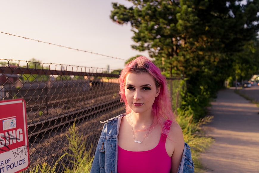 Young Woman with Pink Hair Standing by Train Tracks