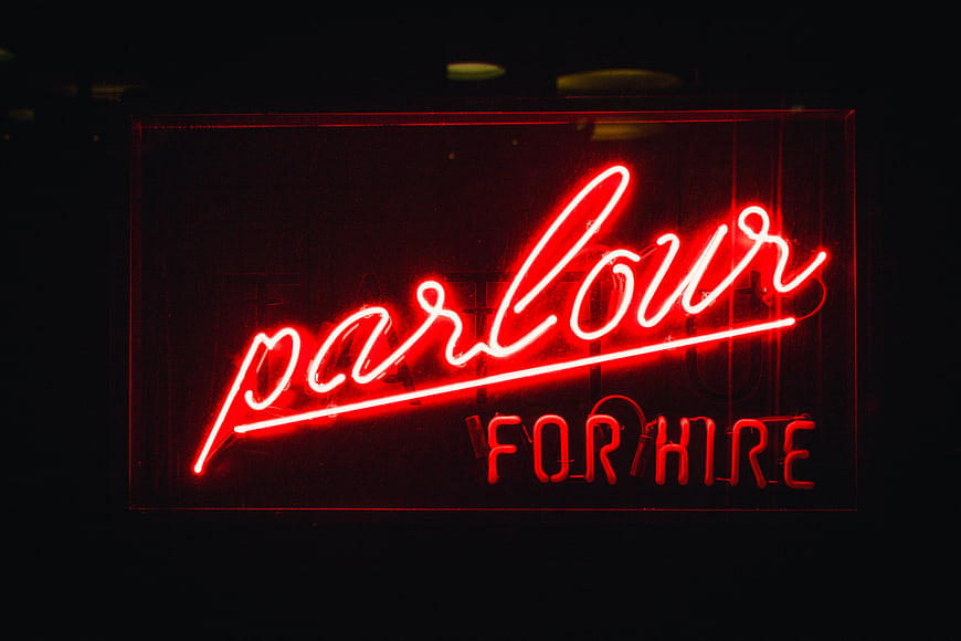 Red Neon Parlour For Hire Sign in Dark Night