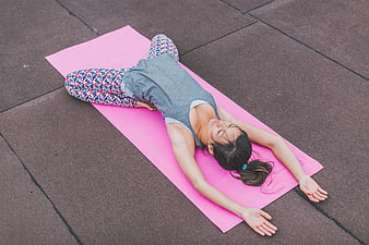 Woman stretching on pink yoga mat outdoors