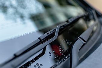 Close-up of car windshield wipers with raindrops on glass