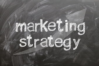 Marketing strategy text written in chalk on a blackboard with arrow