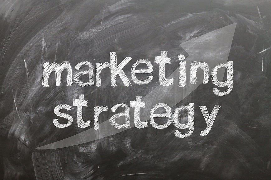 Marketing strategy text written in chalk on a blackboard with arrow