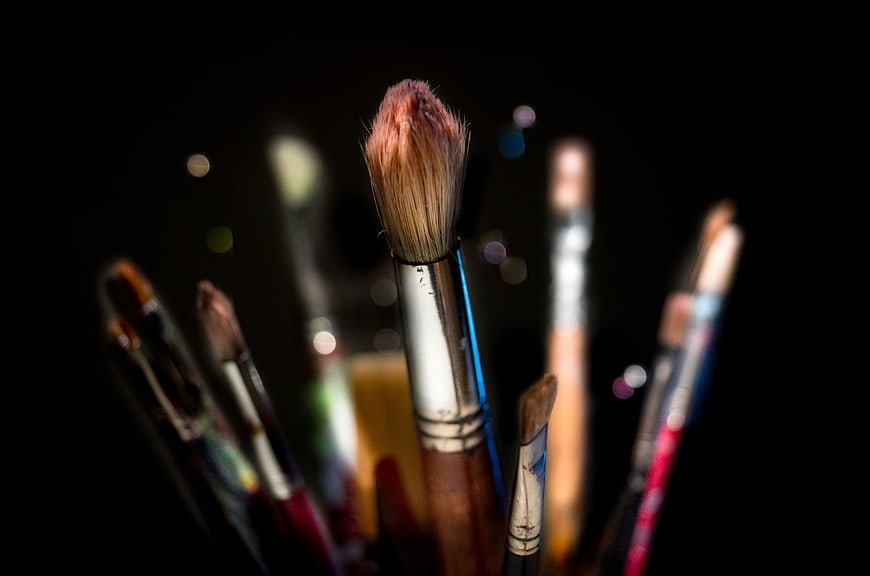 Close-up of paintbrushes with colorful bristles on black background