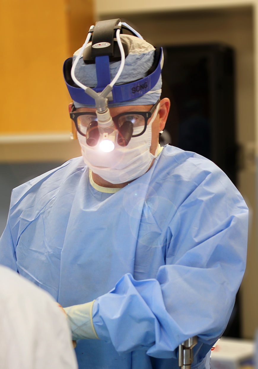 Surgeon with Headlamp in Blue Scrubs Performing Operation