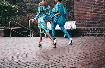 Two Women Walking in Blue Patterned Outfits on Brick Path