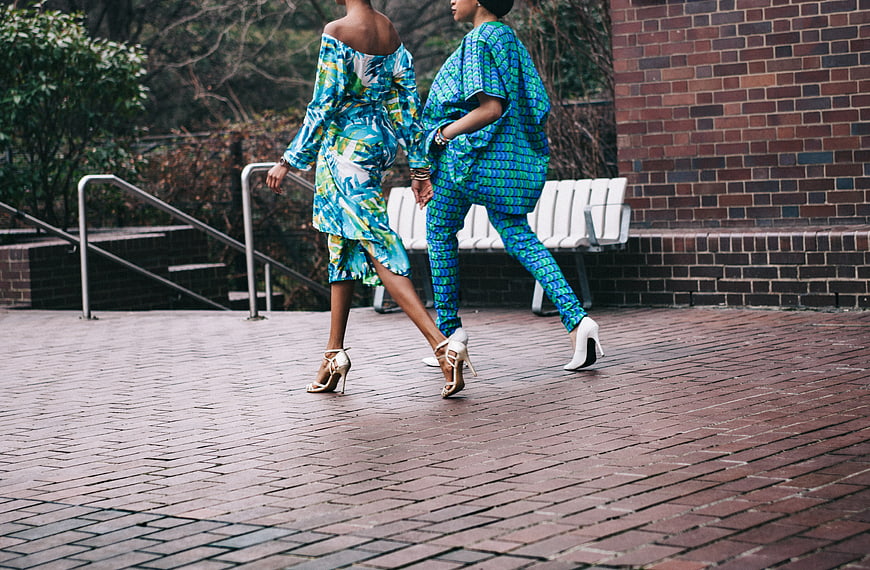 Two Women Walking in Blue Patterned Outfits on Brick Path