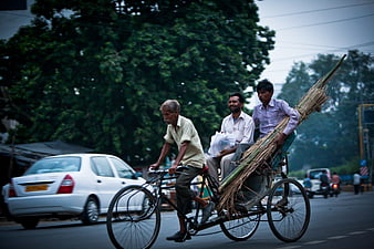 Men Riding Cycle Rickshaw With Bamboo Load On City Street