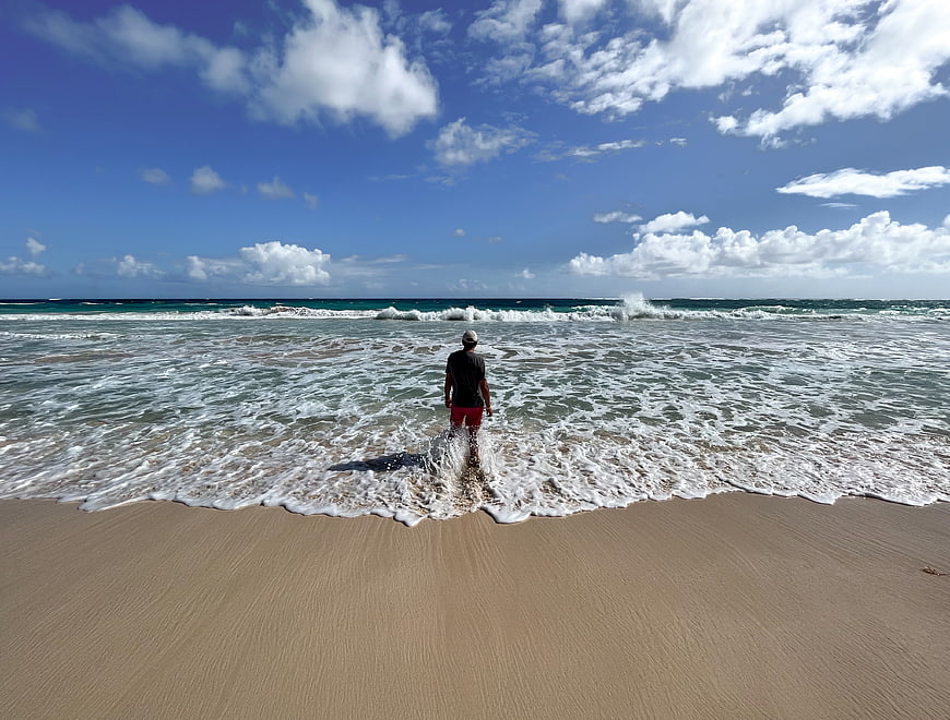 Man Standing in Ocean Waves on Sandy Beach