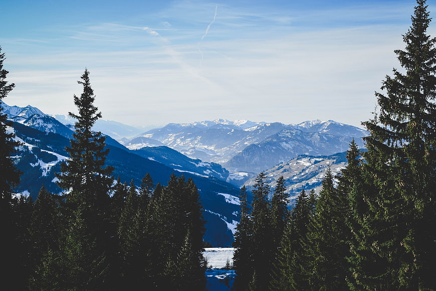Snowy mountain landscape with pine trees and blue sky