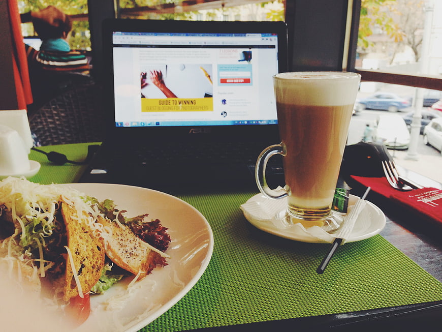 Laptop, salad, and iced latte on a cafe table
