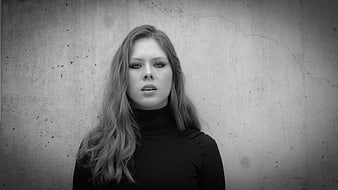 Dramatic black and white portrait of a young woman against concrete