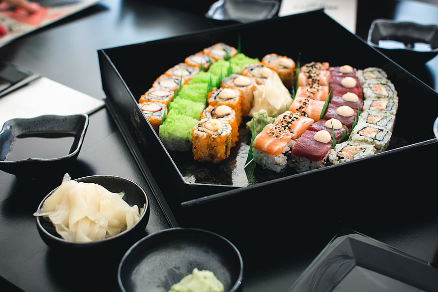 Assorted sushi platter in black box with soy sauce and ginger