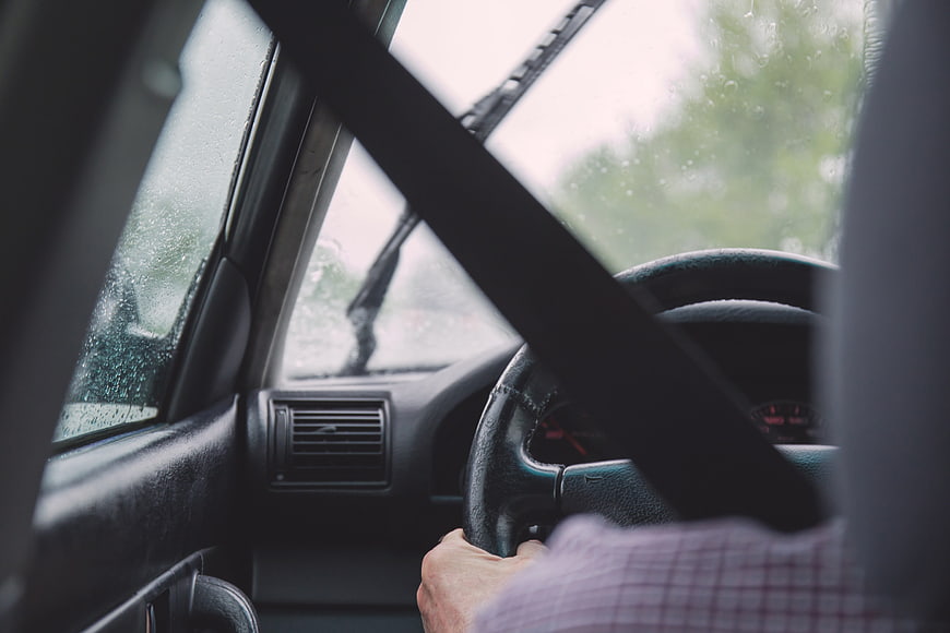 Man driving car in rain with seatbelt