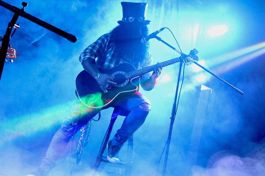 Guitarist in Top Hat Performing Live on Stage with Blue Lighting