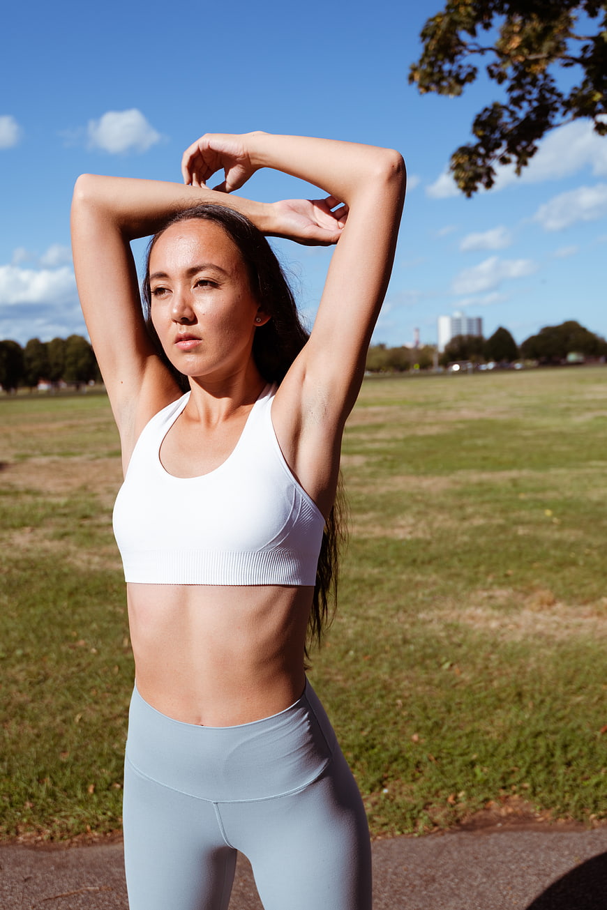 Woman stretching arms outdoors in fitness gear