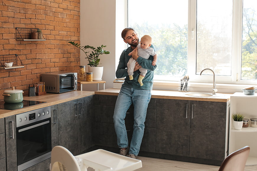Happy Father Holding Baby in Modern Kitchen