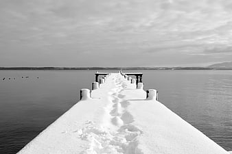 Snowy Dock with Footprints Leading to Calm Lake
