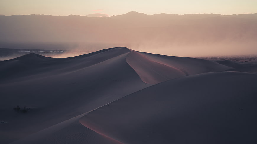 Aerial View of Sand Dunes at Sunset with Distant Mountains