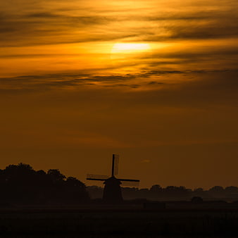 Silhouette of Dutch Windmill Against Golden Sunrise Sky